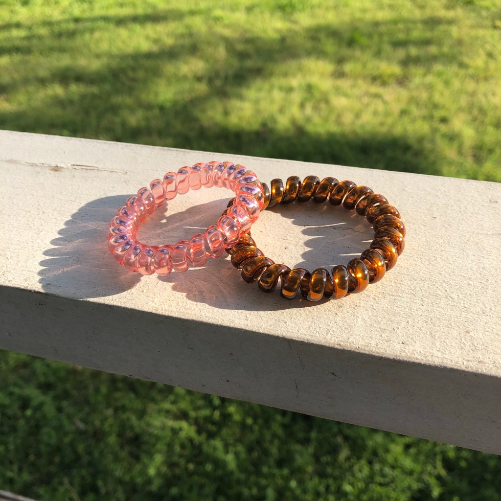 Picture of rubber/plastic hair coils in clear pink and copper colors.